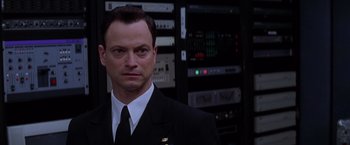 Movie still from “Snake Eyes” (1998), directed by Brian De Palma – A man wearing a suit and tie standing in front of a bunch of computer equipment; Close Up shot, Low angle