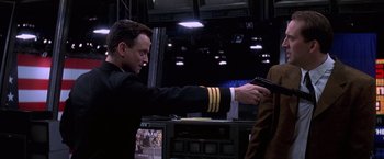 Movie still from “Snake Eyes” (1998), directed by Brian De Palma – A man holding a gun in his right hand while standing next to another man; Medium shot, Over the shoulder angle