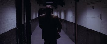Movie still from “Snake Eyes” (1998), directed by Brian De Palma – A man walking down a hallway in a dark room; Wide shot, Low angle