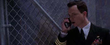 Movie still from “Snake Eyes” (1998), directed by Brian De Palma – A man talking on a cell phone next to a chain link fence; Close Up shot, Low angle