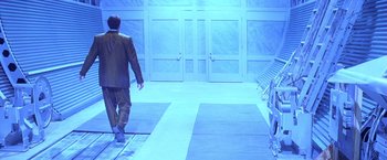 Movie still from “Snake Eyes” (1998), directed by Brian De Palma – A man walking down a runway in a suit; Wide shot, Low angle