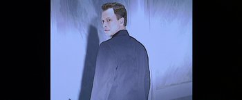 Movie still from “Snake Eyes” (1998), directed by Brian De Palma – A man in a suit standing in front of a wall; Medium shot, Low angle