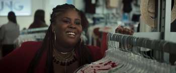 Movie still from “Snatched” (2017), directed by Jonathan Levine – A woman smiling while holding a rack of clothes; Close Up shot, Over the shoulder angle