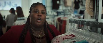 Movie still from “Snatched” (2017), directed by Jonathan Levine – A woman in a red jacket is looking at clothes on hangers in a store; Close Up shot, Over the shoulder angle