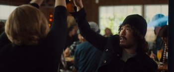 Movie still from “Snatched” (2017), directed by Jonathan Levine – A man in black jacket raising his hands in the air; Medium shot, Over the shoulder angle