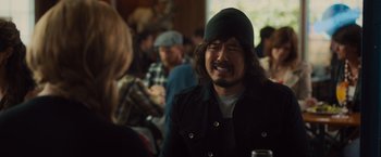 Movie still from “Snatched” (2017), directed by Jonathan Levine – A man with a beard and a hat is talking to some people; Close Up shot, Over the shoulder angle