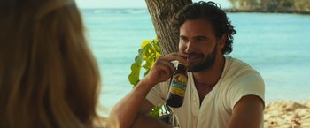 Movie still from “Snatched” (2017), directed by Jonathan Levine – A man sitting next to a tree holding a bottle of beer; Close Up shot, Over the shoulder angle