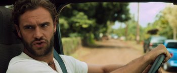 Movie still from “Snatched” (2017), directed by Jonathan Levine – A man sitting in the drivers seat of a car driving down a road; Close Up shot, Over the shoulder angle