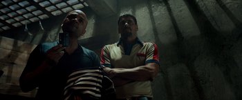 Movie still from “Snatched” (2017), directed by Jonathan Levine – Two men standing next to each other in a dark room; Medium shot, Low angle