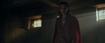 Movie still from “Snatched” (2017), directed by Jonathan Levine – A man standing in a dark room wearing a red shirt; Medium shot, Low angle
