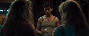 Movie still from “Snatched” (2017), directed by Jonathan Levine – A man in a tank top is holding something in front of two other people; Medium shot, Over the shoulder angle