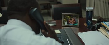 Movie still from “Snatched” (2017), directed by Jonathan Levine – A person sitting at a desk with a picture of a child in the background; Extreme Close Up shot, High angle