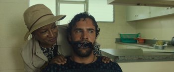 Movie still from “Snatched” (2017), directed by Jonathan Levine – A man with curly hair and a mustache is being held by a woman; Close Up shot, Over the shoulder angle
