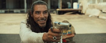 Movie still from “Snatched” (2017), directed by Jonathan Levine – A man with long hair holding a gun in his hand; Close Up shot, Over the shoulder angle