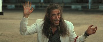 Movie still from “Snatched” (2017), directed by Jonathan Levine – A man with long black hair and a white jacket; Medium shot, Over the shoulder angle