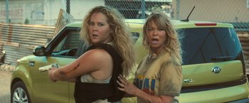Movie still from “Snatched” (2017), directed by Jonathan Levine – Two women are fighting in front of a yellow car; Medium shot, Over the shoulder angle