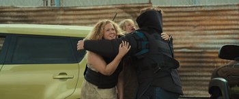 Movie still from “Snatched” (2017), directed by Jonathan Levine – A woman is hugging a man and another woman is hugging another man; Medium shot, Over the shoulder angle