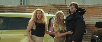 Movie still from “Snatched” (2017), directed by Jonathan Levine – A group of people standing next to each other near a yellow car; Medium shot, Over the shoulder angle