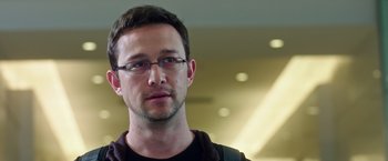 Movie still from “Snowden” (2016), directed by Oliver Stone – A person wearing glasses and a black shirt; Close Up shot, Over the shoulder angle