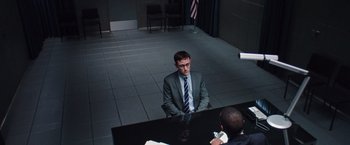 Movie still from “Snowden” (2016), directed by Oliver Stone – A man sitting at a table in front of a piano; Medium shot, Over the shoulder angle