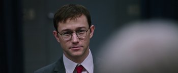 Movie still from “Snowden” (2016), directed by Oliver Stone – A man in a suit and tie wearing glasses; Close Up shot, Over the shoulder angle