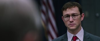 Movie still from “Snowden” (2016), directed by Oliver Stone – A person wearing a suit and glasses; Close Up shot, Over the shoulder angle
