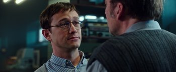Movie still from “Snowden” (2016), directed by Oliver Stone – A man wearing glasses talking to another man in a room; Close Up shot, Over the shoulder angle