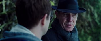 Movie still from “Snowden” (2016), directed by Oliver Stone – A man wearing a hat and glasses talking to another man; Close Up shot, Over the shoulder angle