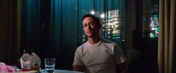 Movie still from “Snowden” (2016), directed by Oliver Stone – A man sitting at a table in front of a glass of water; Medium shot, Over the shoulder angle