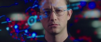 Movie still from “Snowden” (2016), directed by Oliver Stone – A person wearing glasses and a black shirt; Close Up shot, Over the shoulder angle