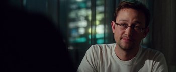 Movie still from “Snowden” (2016), directed by Oliver Stone – A person wearing glasses sitting in a room; Close Up shot, Over the shoulder angle