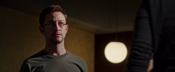 Movie still from “Snowden” (2016), directed by Oliver Stone – A person wearing glasses in a room; Close Up shot, Low angle