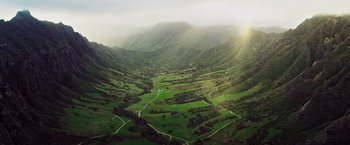 Movie still from “Snowden” (2016), directed by Oliver Stone – A view of a lush green valley from a helicopter; Extreme Wide shot, High angle