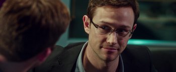 Movie still from “Snowden” (2016), directed by Oliver Stone – A person wearing glasses and a suit jacket; Close Up shot, Over the shoulder angle