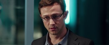 Movie still from “Snowden” (2016), directed by Oliver Stone – A person wearing glasses and a suit; Close Up shot, Over the shoulder angle