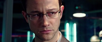 Movie still from “Snowden” (2016), directed by Oliver Stone – A person wearing glasses and a suit; Close Up shot, Over the shoulder angle