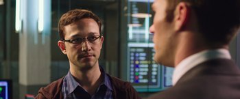 Movie still from “Snowden” (2016), directed by Oliver Stone – A man wearing glasses talking to another man in front of a computer screen; Close Up shot, Over the shoulder angle