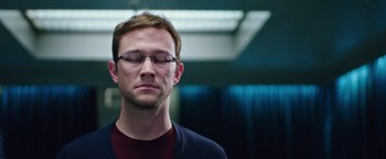 Movie still from “Snowden” (2016), directed by Oliver Stone – A man with glasses is looking down at his eyes; Close Up shot, Low angle