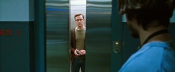 Movie still from “Snowden” (2016), directed by Oliver Stone – A man standing in an elevator holding a cell phone; Medium shot, Low angle