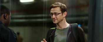 Movie still from “Snowden” (2016), directed by Oliver Stone – A man with glasses is standing in front of a building; Close Up shot, Over the shoulder angle