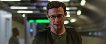 Movie still from “Snowden” (2016), directed by Oliver Stone – A person wearing glasses and a jacket; Close Up shot, Over the shoulder angle