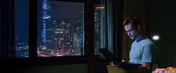 Movie still from “Snowden” (2016), directed by Oliver Stone – A person sitting at a table with a laptop in front of a window; Medium shot, High angle