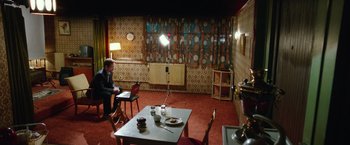 Movie still from “Snowden” (2016), directed by Oliver Stone – A man sitting at a table in front of a lamp; Wide shot, High angle