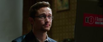 Movie still from “Snowden” (2016), directed by Oliver Stone – A person wearing glasses and a suit; Close Up shot, Over the shoulder angle
