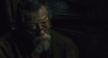 Movie still from “Snowpiercer” (2013), directed by Bong Joon Ho – An old man with a gray beard wearing glasses; Close Up shot, Low angle