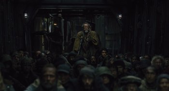 Movie still from “Snowpiercer” (2013), directed by Bong Joon Ho – A group of people in a dark room; Medium shot, High angle