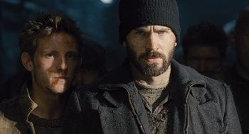 Movie still from “Snowpiercer” (2013), directed by Bong Joon Ho – A man with a beard wearing a black hat and jacket; Close Up shot, Low angle