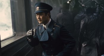 Movie still from “Snowpiercer” (2013), directed by Bong Joon Ho – A man in a uniform is standing in front of a window; Medium shot, Low angle