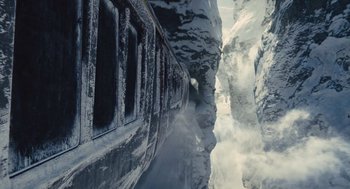 Movie still from “Snowpiercer” (2013), directed by Bong Joon Ho – A train traveling down a snow - covered mountain side; Extreme Wide shot, Overhead angle