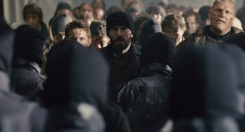 Movie still from “Snowpiercer” (2013), directed by Bong Joon Ho – A group of people standing around each other in a crowd; Medium shot, Over the shoulder angle